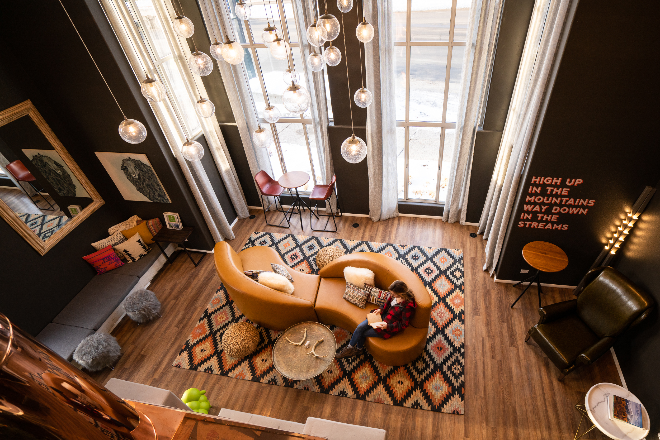 Looking down on a warm hotel lobby with a sofa in the centre, a patterned rug and hanging light features