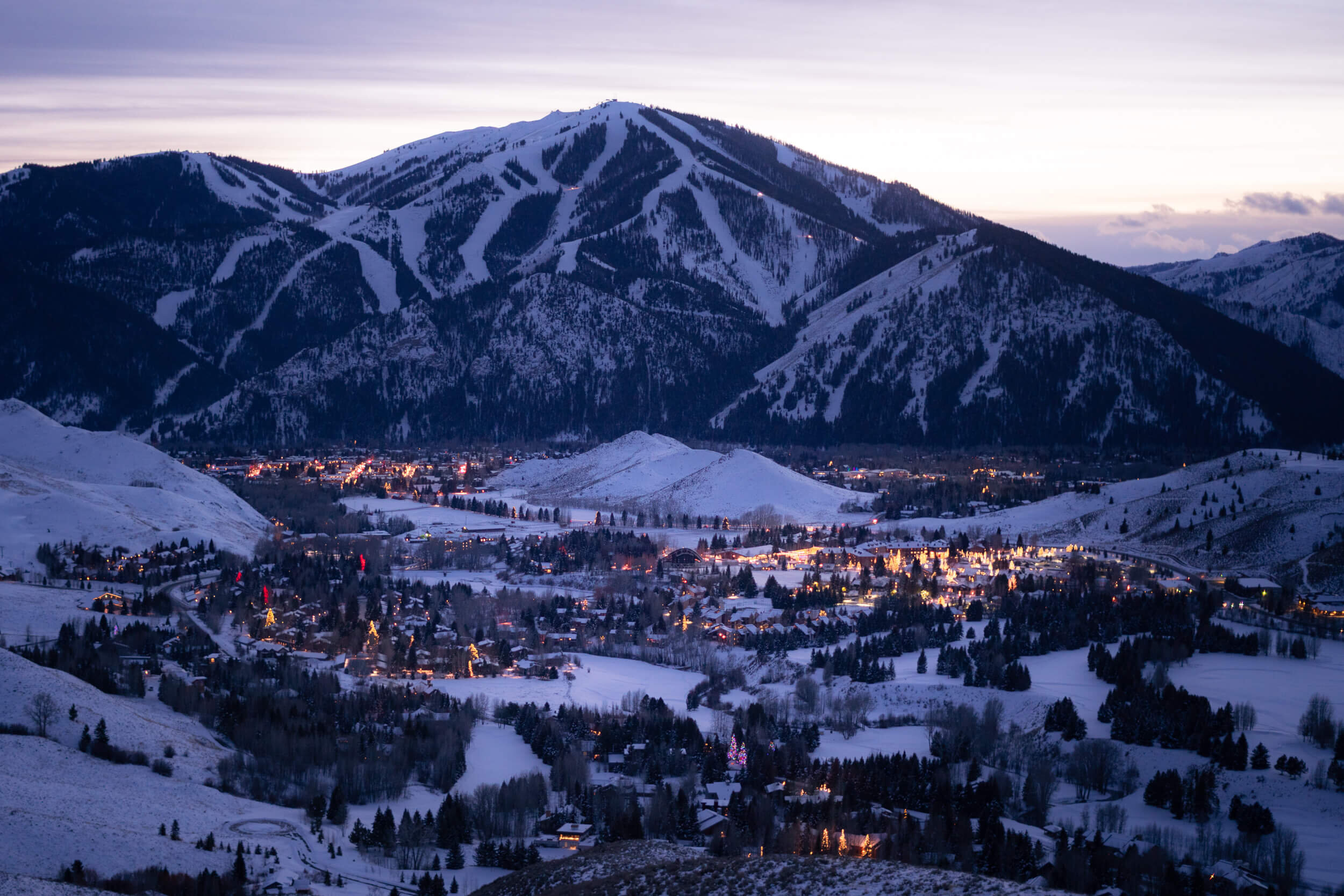 Sun Valley ski resort at lit up at night in the base of the valley surrounded by mountains covered in snow.