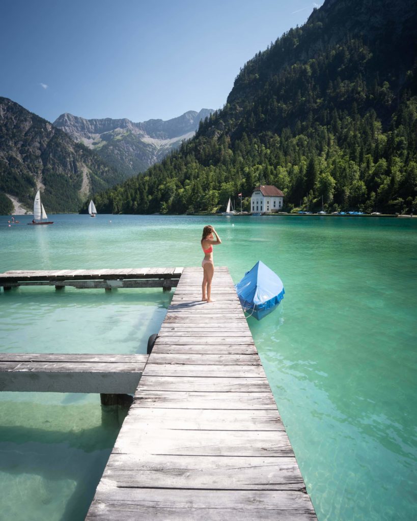 Jess standing on a wooden dock surrounded by clear water and large green tree covered hills in the distance