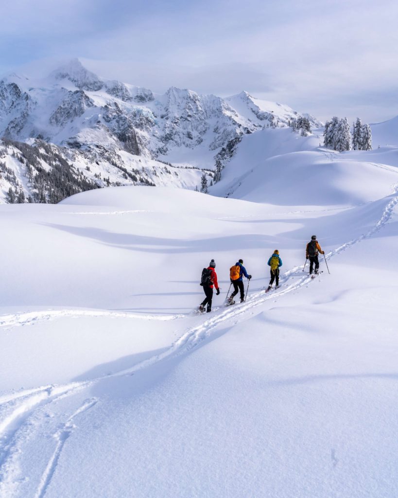 four people snowshoing up artists point on mount baker in washington state