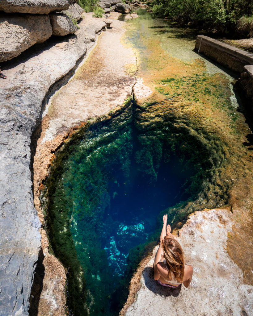 A water hole with a deep blue cave below the water