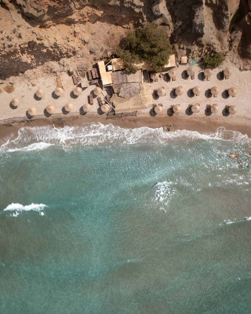 Umbrellas and lawn chairs line the beach at Firiplaka on Milos Island. 