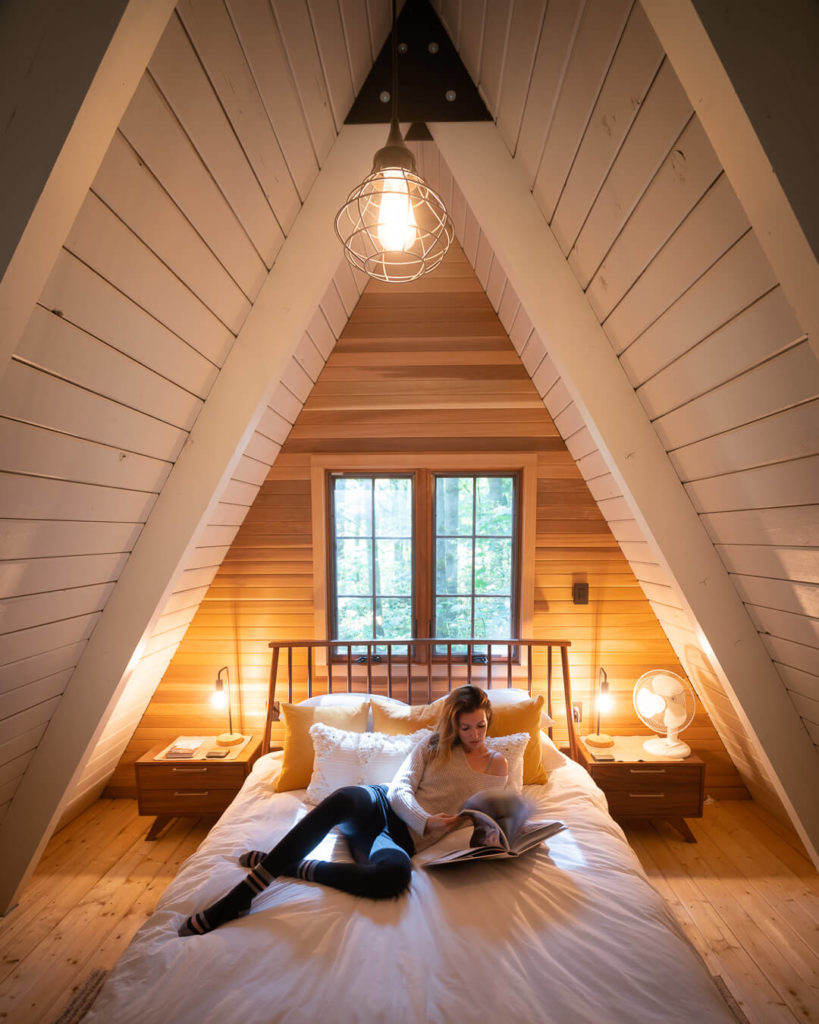 woman reading in bed in an a frame cabin in washington
