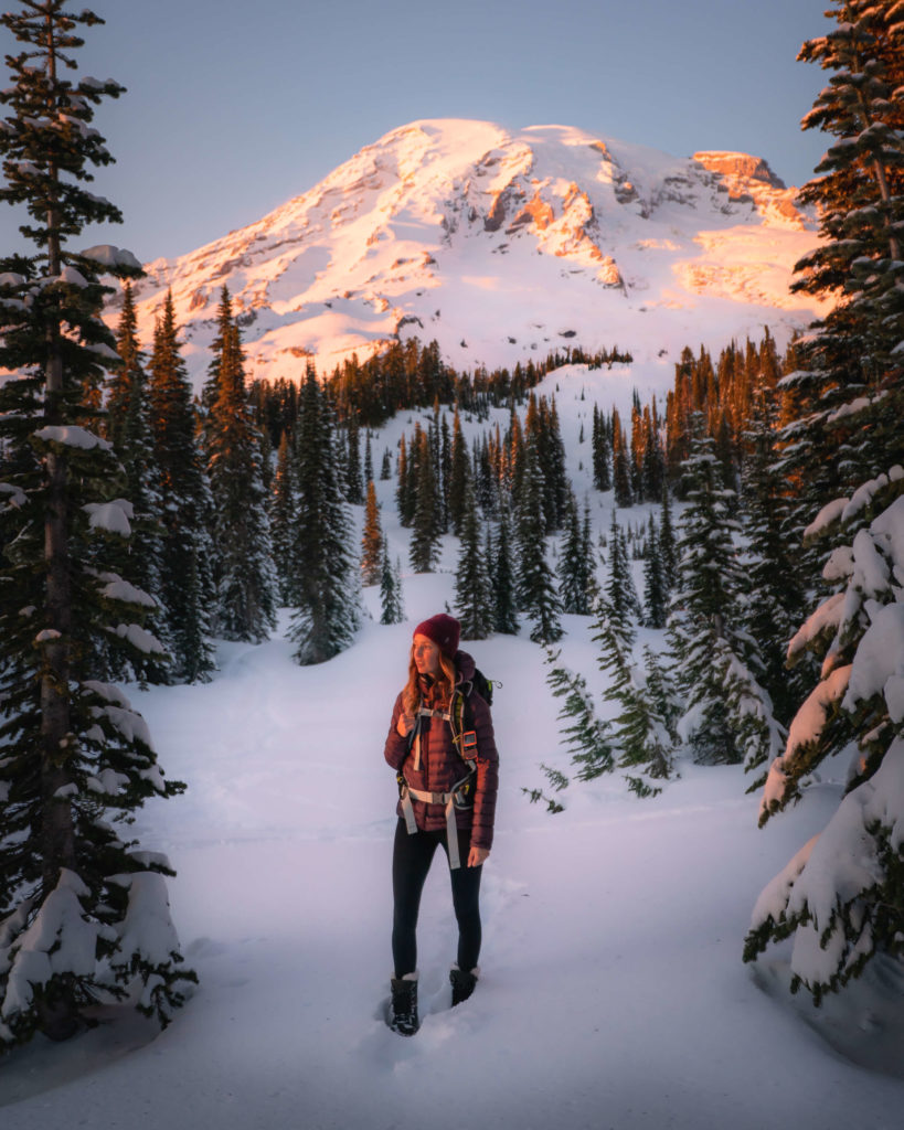 Jess standing in a snowy landscape wearing winter hiking gear and fleece leggings
