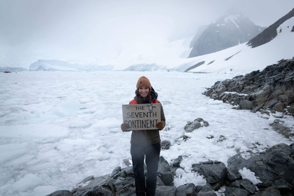 Holding a sign that reads "The Seventh Continent" during an Antarctic landing
