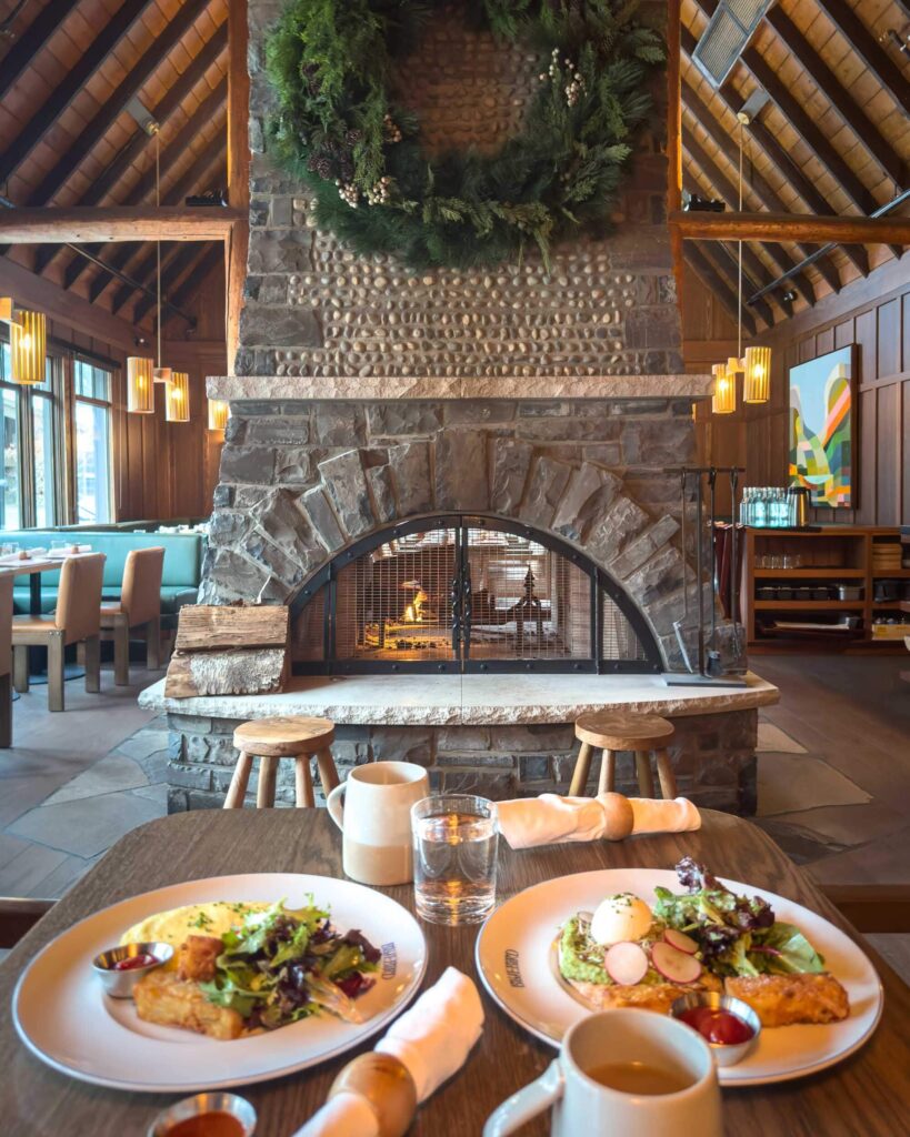 A restaurant interior with a large stone fireplace and two plates of food on the table