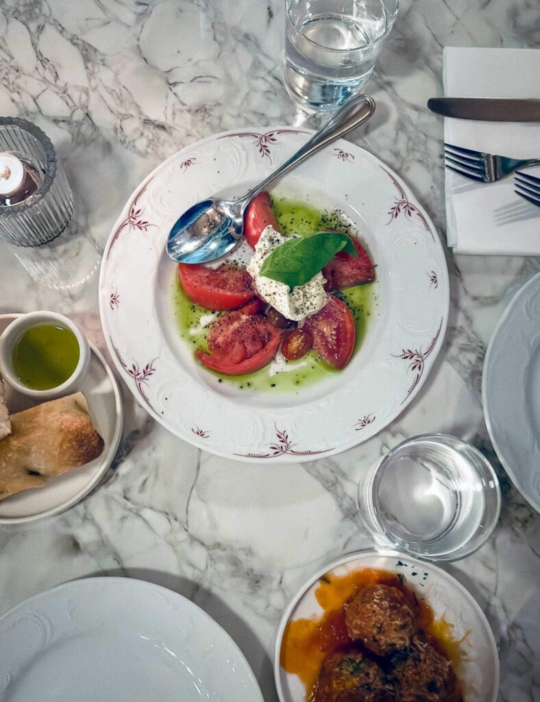 A plate with tomatoes, mozzarella and a green dressing