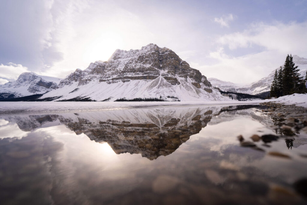 A snow covered mountain reflected in a still, glassy lake as we explored winter activities in Banff Canada