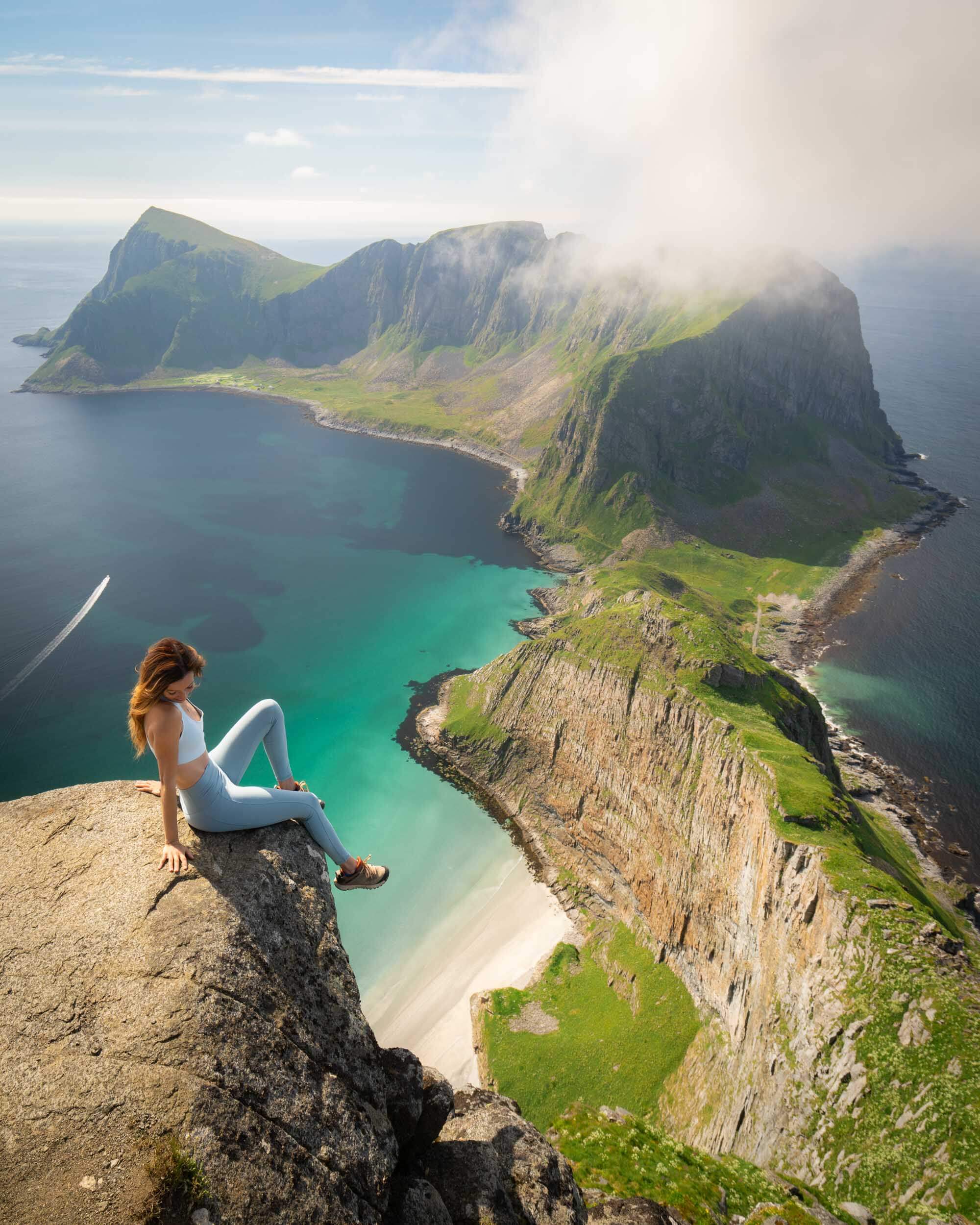 Jess wandering sitting on edge overlooking one of the best lofoten islands hikes